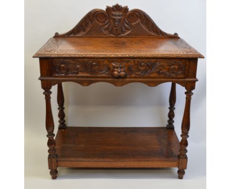 A heavily carved light oak hall table, having carved and shaped figural top rail, carved border to rectangular top with long 