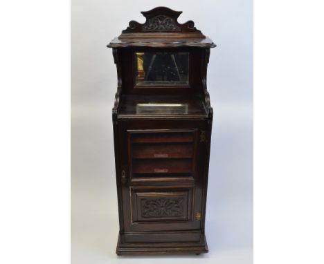 A mahogany music cabinet, having shelf over raised mirror back, five shelves under with glazed door with carved panel to base