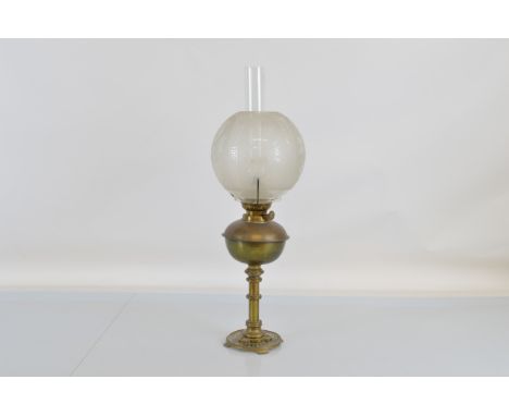 A brass oil lamp, with etched glass bowl form shade and central flue. 58cm tall