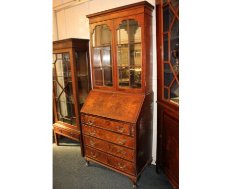 A walnut bureau bookcase, with dentil carved cornice above mirror backed interior with two shelves enclosed by twin panel gla