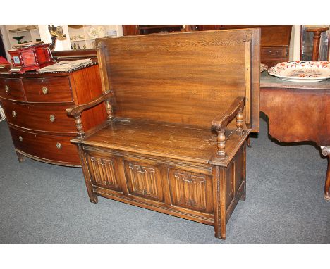 A 20th century oak monk's bench with hinged back and seat, the front with three linen fold carved panels, on block feet, 117c