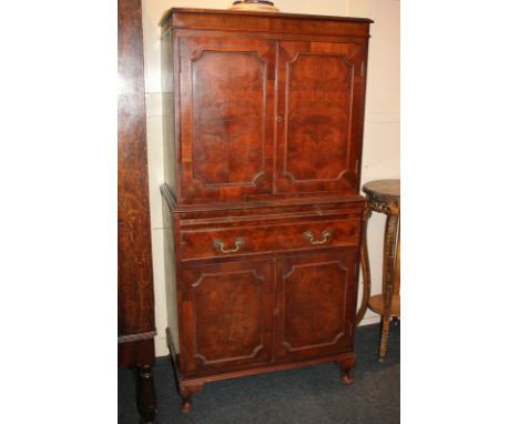 A reproduction walnut cocktail cabinet with two panel doors enclosing mirror-backed interior (shelves missing), on base with 