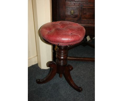 An adjustable piano stool with button upholstered circular leather top, on baluster turned stem and outswept tripod legs