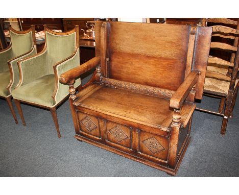 An oak monk's bench with hinged back and seat, the-three panel front carved with foliate diamond motifs, on block feet
