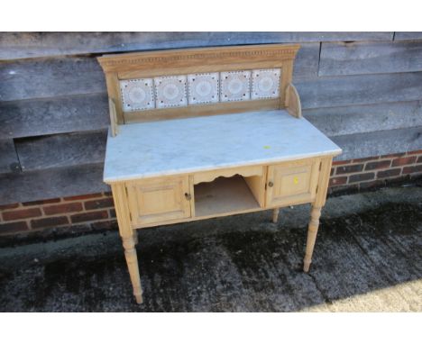 A pine washstand with tile back and marble top over cupboards and recess, on turned supports, 36" wide x 20" deep x 40" high