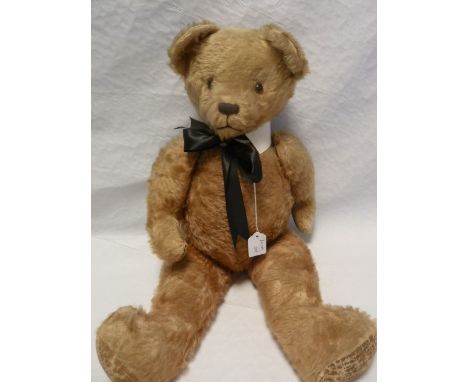 Large gold plush straw stuffed bear with glass eyes and a stitched nose and mouth with a white stiff collar and black bow 68c