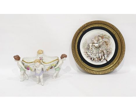 Continental porcelain two-dimensional plaque, pair lovers seated beside tree trunk wearing floral decorated dress, 26cm diame