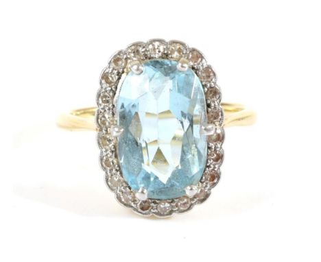 An Aquamarine and Diamond Cluster Ring, an oval cut aquamarine in a claw setting, within a border of milgrain set eight-cut d