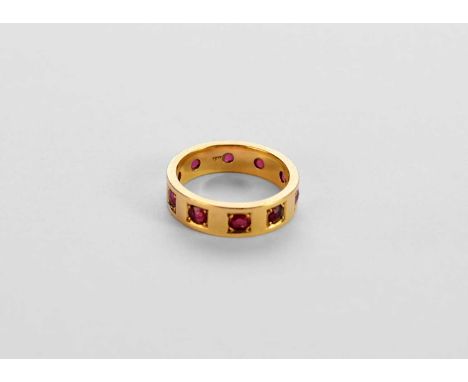 A yellow metal ruby set eternity band, the round mixed cut rubies box set within yellow metal band, stamped '18', ring size N