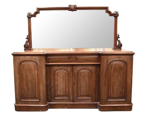 A mid-Victorian mahogany mirror-back breakfront sideboard, The full-width plate within an ogee frame with scroll spandrels, t