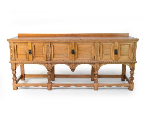 A 20th century, Renaissance style, pale oak dresser base, with foliate carved arches and stiles, the rectangular top above a 