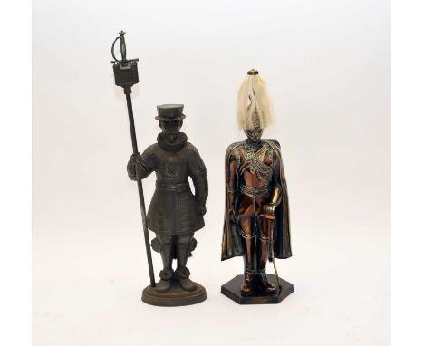 Two cast iron standing fireside figural tool caddies, the first modelled as a Beefeater holding a tower staff containing a 's