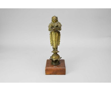 An Indian Brass Figure of Lakshmi / Deepalakshmi, 19th century, modelled standing and holding a deepa butter lamp dish, weari
