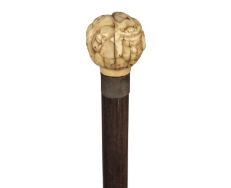 * Walking Stick. A Japanese ivory top cane, Meiji period (1868-1912), the spherical top carved with multiples masks on a rose