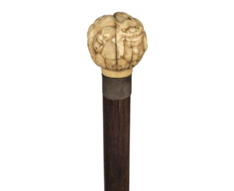 * Walking Stick. A Japanese ivory top cane, Meiji period (1868-1912), the spherical top carved with multiples masks on a rose