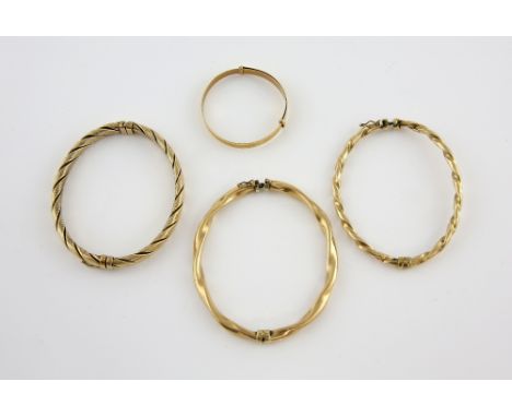 Four gold bangles, three twisted oval hinged bangles, with concealed clasp and figure of eight clasps and an expanding christ