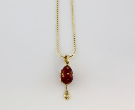Faberge a contemporary gold and enamel egg pendant, the red enamel inlaid with gold stars and opening to reveal a diamond set