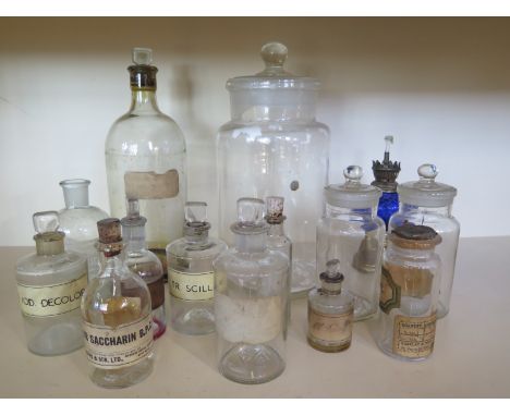 A small collection of 13 glass bottles and an oil lamp with blue reservoir 