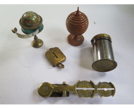 A sovereign scale, postage stamp box scale, magic pocket bank, tape measure on a stand and a treen pot 6cm tall, condition as