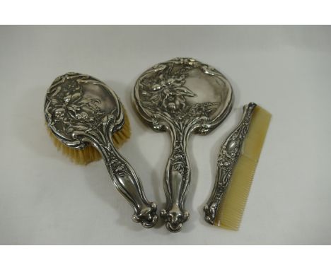 An Art Nouveau silver backed three piece dressing table set, comprised of brush, comb and hand mirror, Birmingham 1909 CONDIT