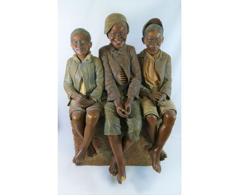 A large Goldscheider pottery model of three boys sitting on a brick wall by B Haniroff, factory stamp to the reverse and sign