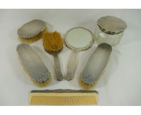 A Continental silver coloured metal backed dressing table set, stamped '.800' comprised of four brushes, a hand mirror and co