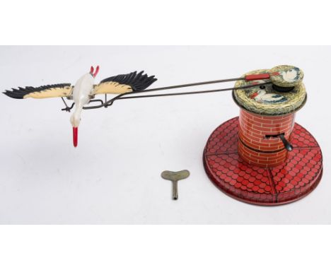An Adebar (West Germany) No 7 tinplate clockwork flying stork:, white and red plastic bodied stork with flapping wings on a l
