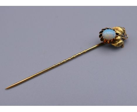 An unmarked gold and opal stick pin. 6 cm high. 1.9 grammes total weight.