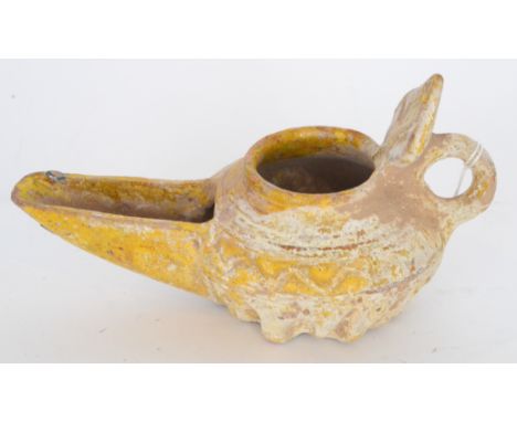 An ancient Islamic terracotta oil lamp with leaf thumb piece above a long spout part yellow glaze remaining, width 15cm.