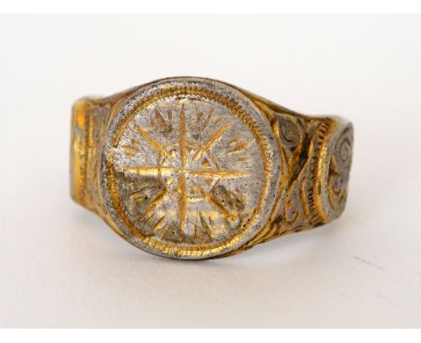 A Continental Saxon silver gilt ring, the flat circular centre carved with a compass point design within a dot border flanked