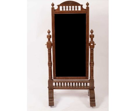 An Arts &amp; Crafts style grained mahogany cheval mirror with an arched rising sun crest above an open bobbin turned panel, 