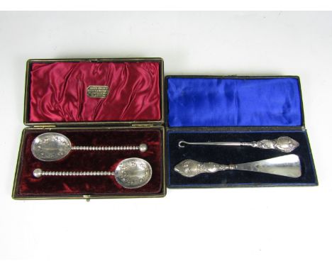 A cased pair of electroplate fruit spoons together with a cased silver handled button hook and shoe horn