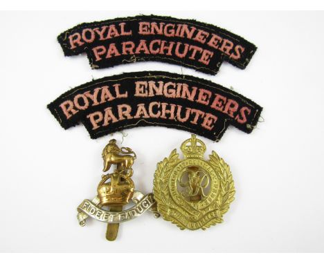 Two British Army cap badges and a pair of reproduction cloth shoulder titles