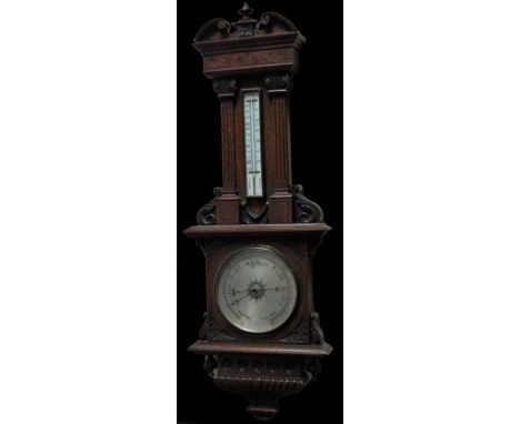 A late 19thC oak cased barometer, the 19cm Dia. silvered dial surmounted by a thermometer in a heavily carved case with broke