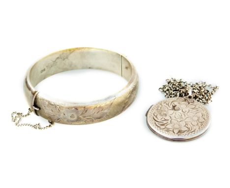 Two items of silver jewellery, to include a silver locket and chain, with floral engraving to front, and a silver bangle.  (2