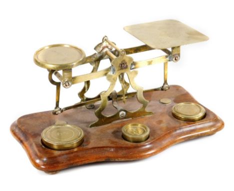 A set of early 20thC brass and mahogany scales, with weights on a serpentine base, 25cm W.