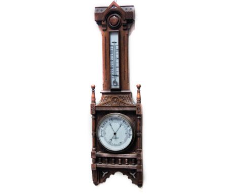 An Edwardian oak cased aneroid barometer and thermometer, the lower 15cm Dia. dial marked H N Luther, Huddersfield, surmounte