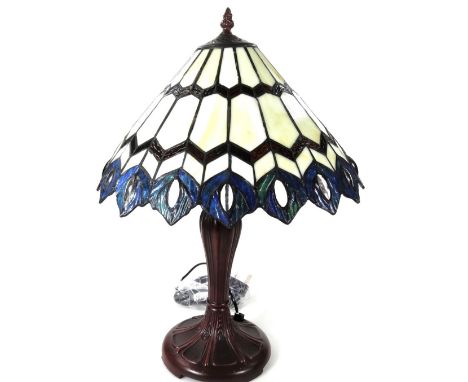 *An as new table lamp, with Tiffany style shade, with repeat peacock feather border predominately in blue, cream and red, 55c