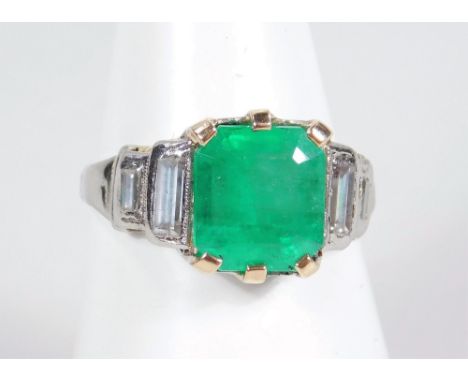 A platinum emerald and diamond dress ring, set with baguette cut emerald, flanked by two baguette cut diamonds to each should