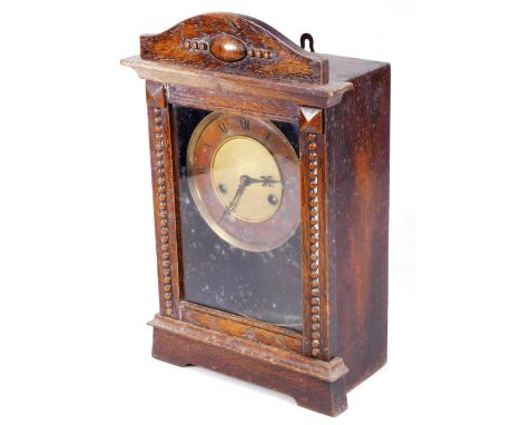 An early 20thC  oak mantel clock, with 13cm Dia. Roman numeric dial fronting a partially exposed 8-day movement, labelled and