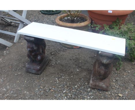 A pair of painted concrete bench bases in the form of squirrels and a wooden board