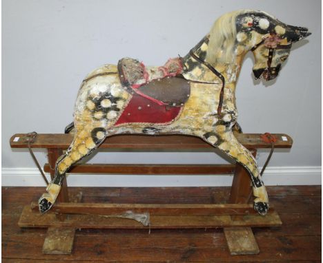 An Edwardian dappled rocking horse, raised on trestle base, leather studded bridle and flower, head loose and in need of rest