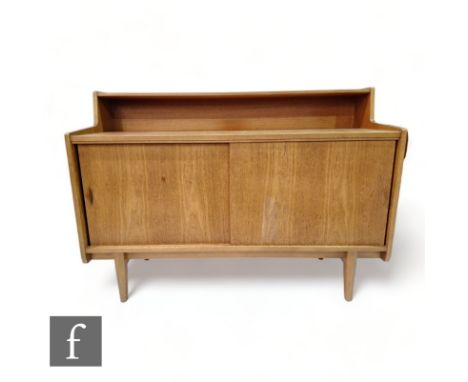 Herbert E. Gibbs - A teak compact cabinet sideboard, with integral ledge shelf above two sliding doors with elliptical handle