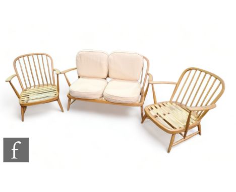 Ercol - A mid Century elm three-piece suite, comprising two Windsor 335 armchairs and two seater sofa, with embroidered cream