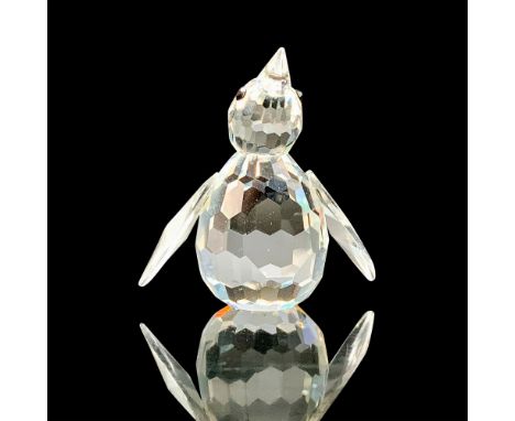 A clear crystal figure of a seated penguin with their arms outstretched by their side and black crystal eyes. Swarovski backs