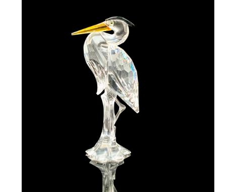 A figure made of clear crystal with accents of black and yellow of a heron perched against some tall grass with its chest out