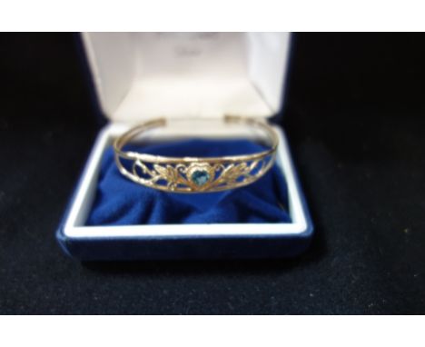 A 9CT YELLOW GOLD TORQUE BANGLE, set an openwork frame with a heart-cut blue 'topaz' (def)