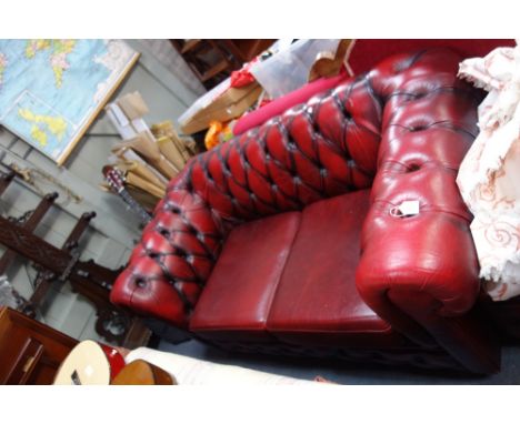 A RED LEATHER BUTTON BACK TWO SEATER CHESTERFIELD and a matching foot stool