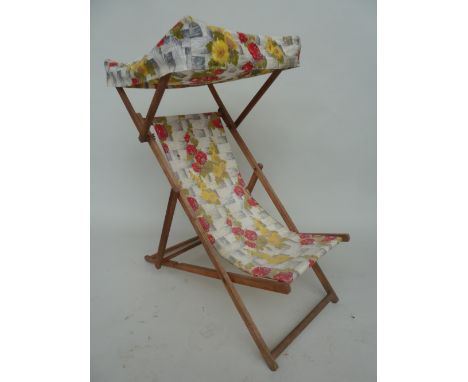 A vintage wooden framed collapsible deck chair with floral fabric seat and cover