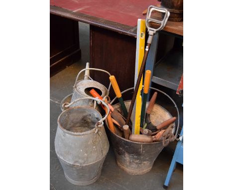 A vintage galvinized metal bucket with various hand tools, shooting stick, another metal bucket, an oil can, torch, a metal p